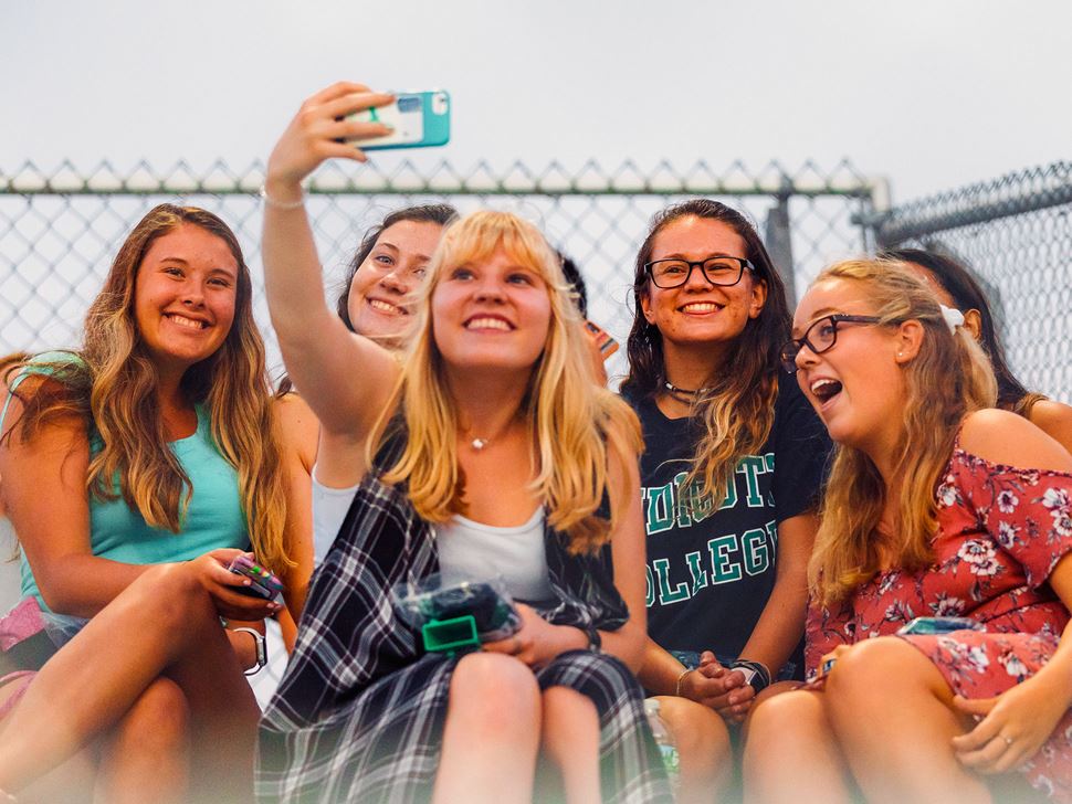 Six students posing for a selfie at an athletic event