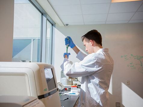 student researching in laboratory with machines and white coat on