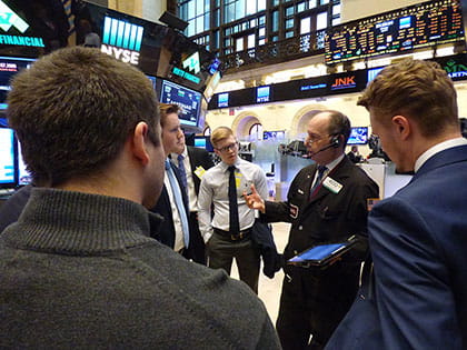 a man talking to a group of business professionals in the stock market exchange