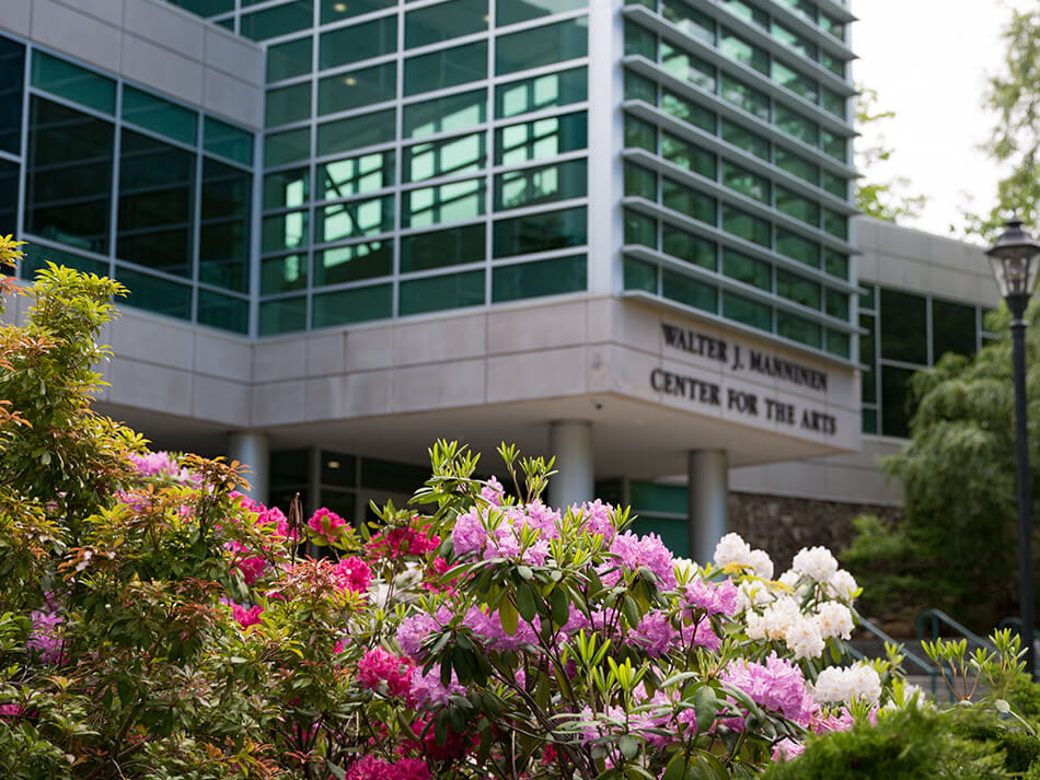 angled shot of the Manninen arts center with flowers blooming in front