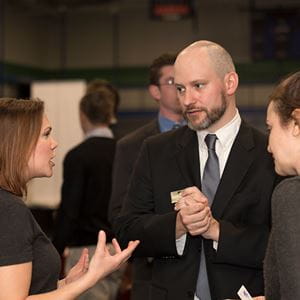 teacher talking to two students at career fair
