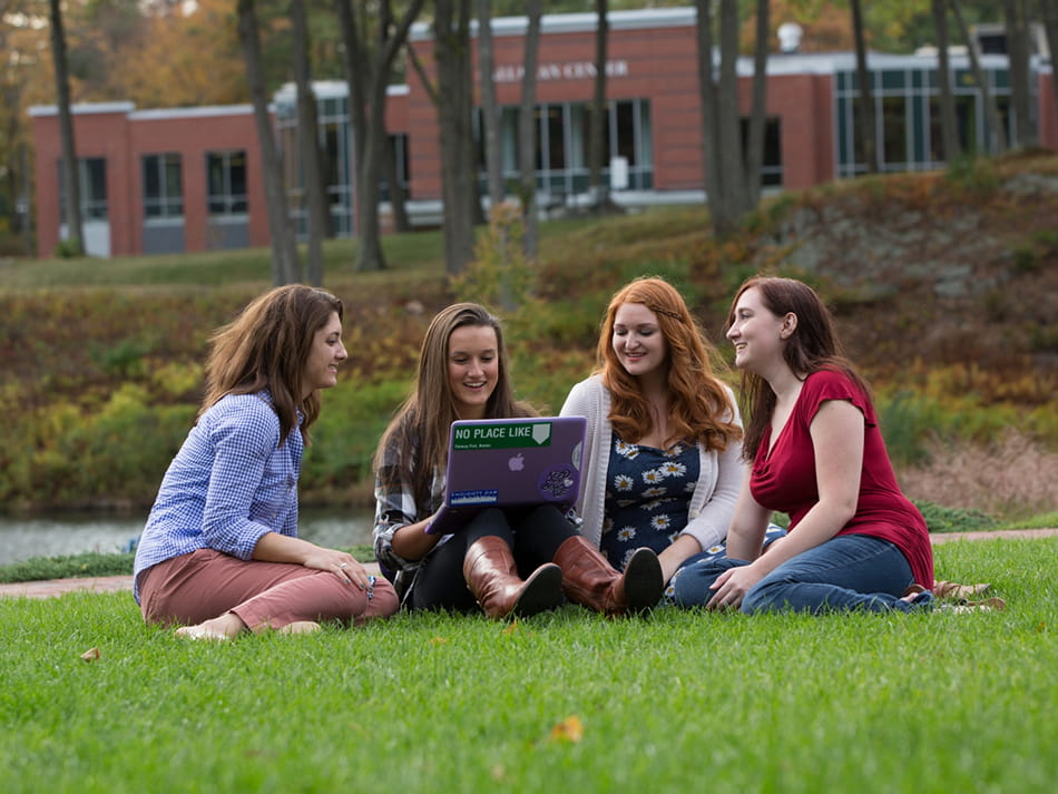 students studying with laptop out in open grassy area