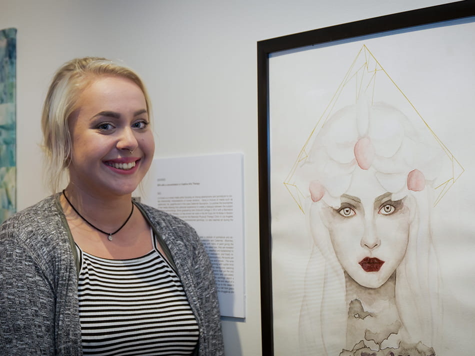 an arts therapy student in front of her portrait