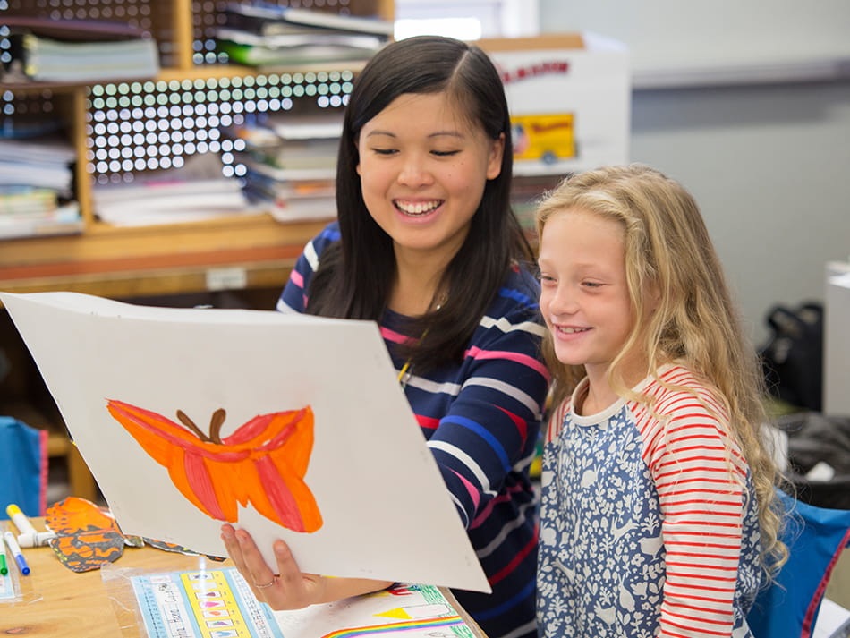 an early childhood education student looking at a kid's butterfly drawing
