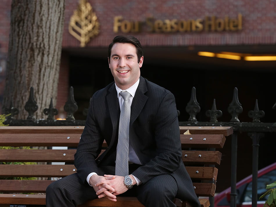 a man in a business suit sitting on a bench in front of the four seasons hotel