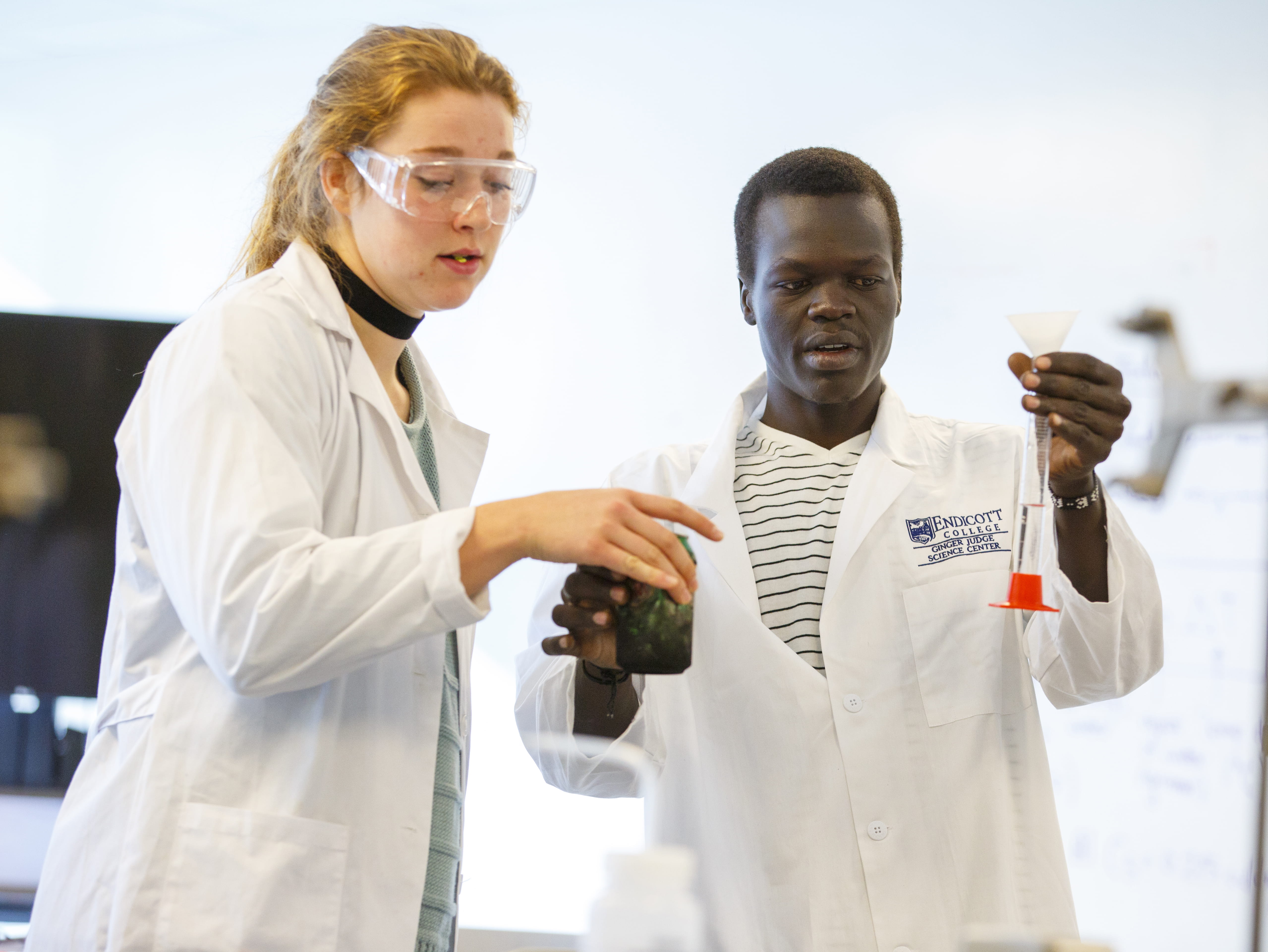 two biology students holding two samples in glass instruments