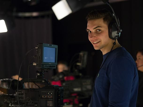 An Endicott College student smiles while filming
