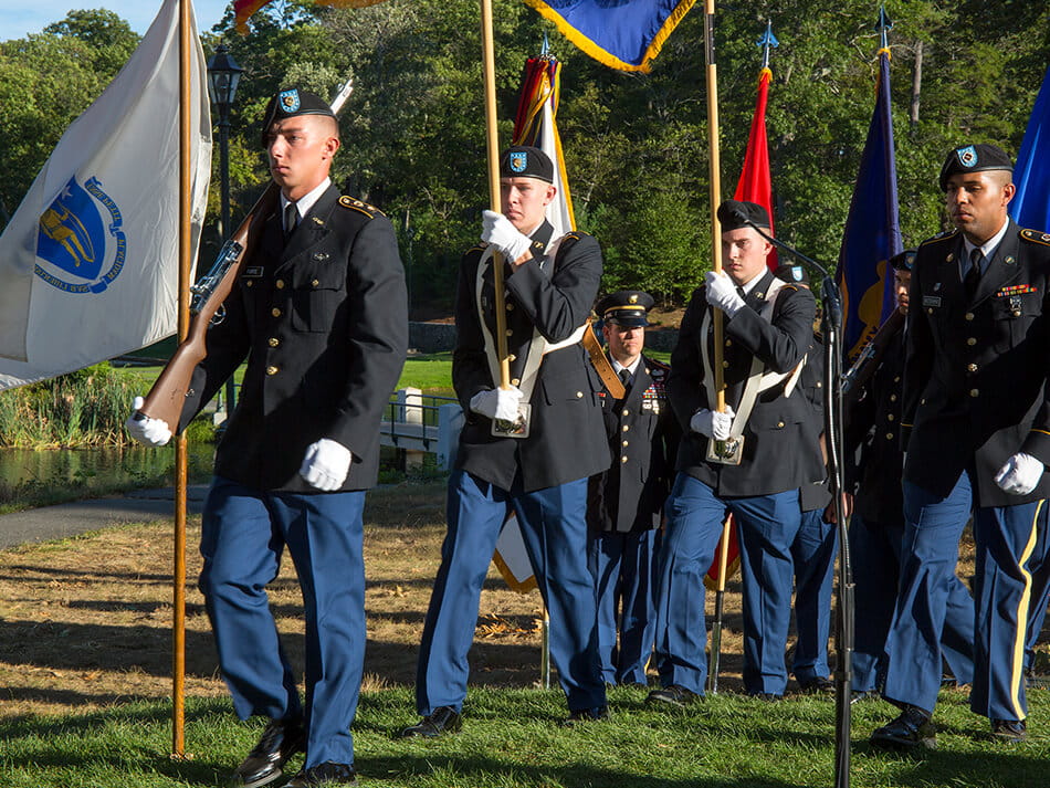 service members in uniform marching with flags