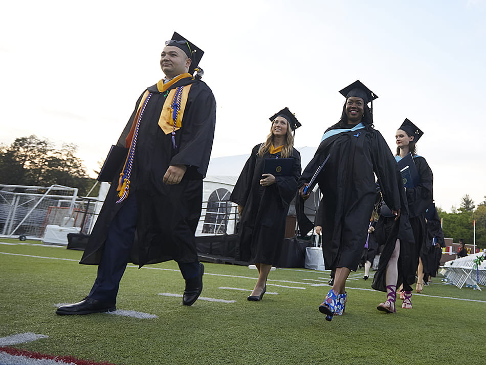 Four students walking out of the Hempstead Stadium following commencement 