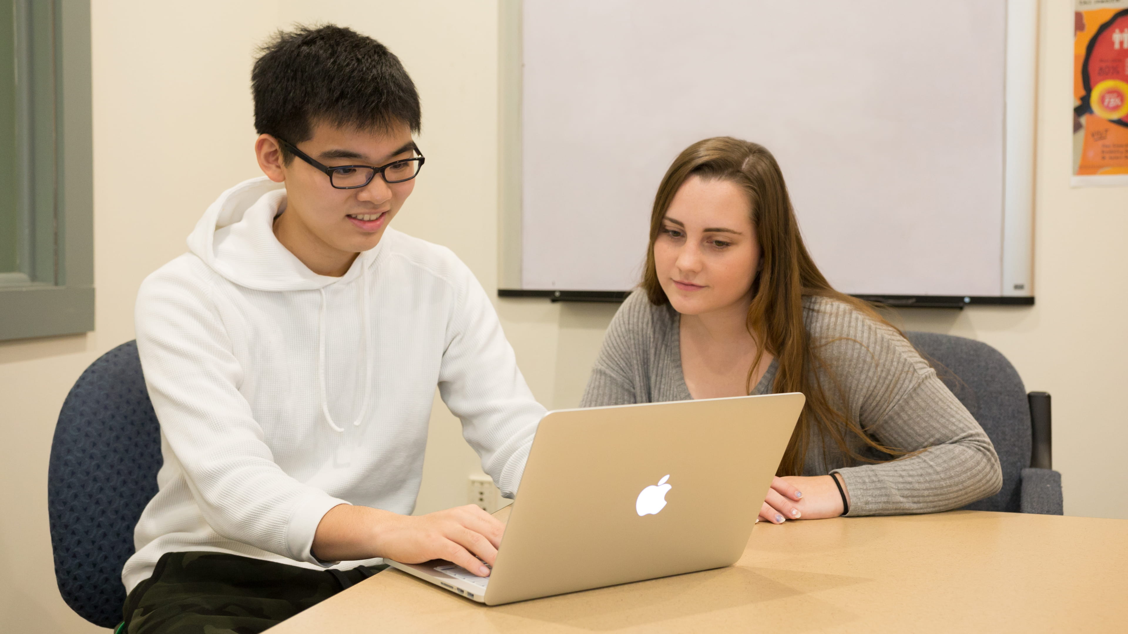 Two students work on laptop in classroom