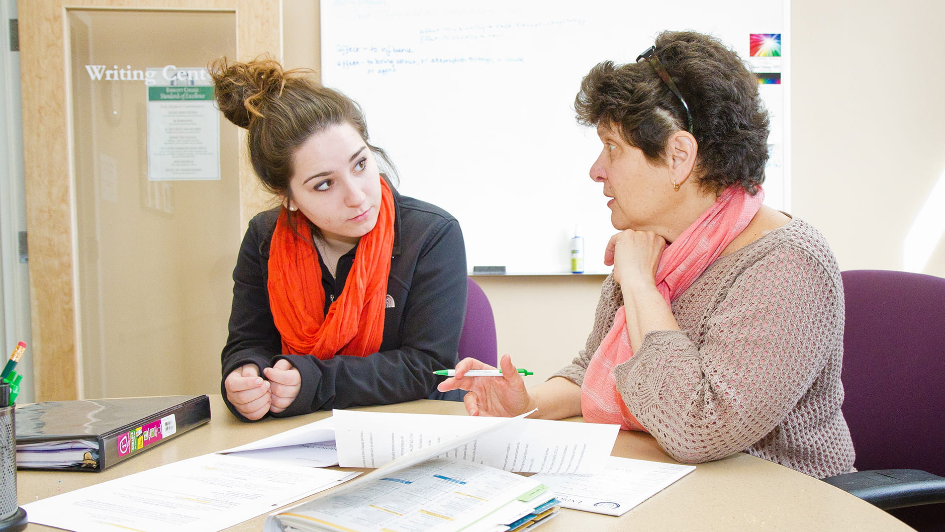Student and Advisor converse while looking over documents and notes in Endicott classroom