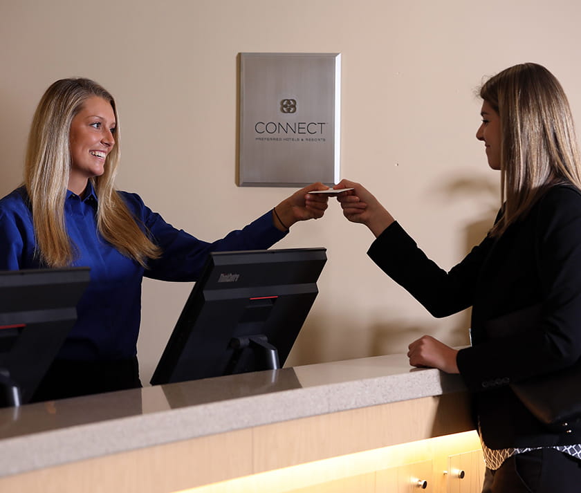 a woman handing a card key to a customer for her hotel room