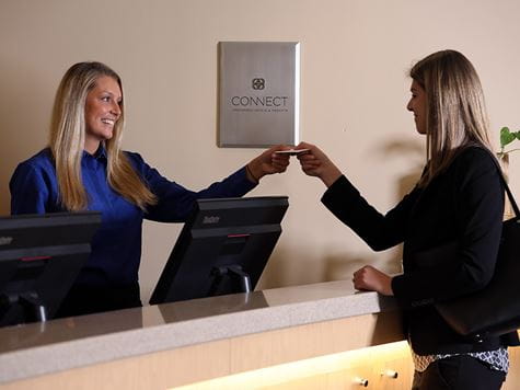 a woman handing a card key to a customer for her hotel room