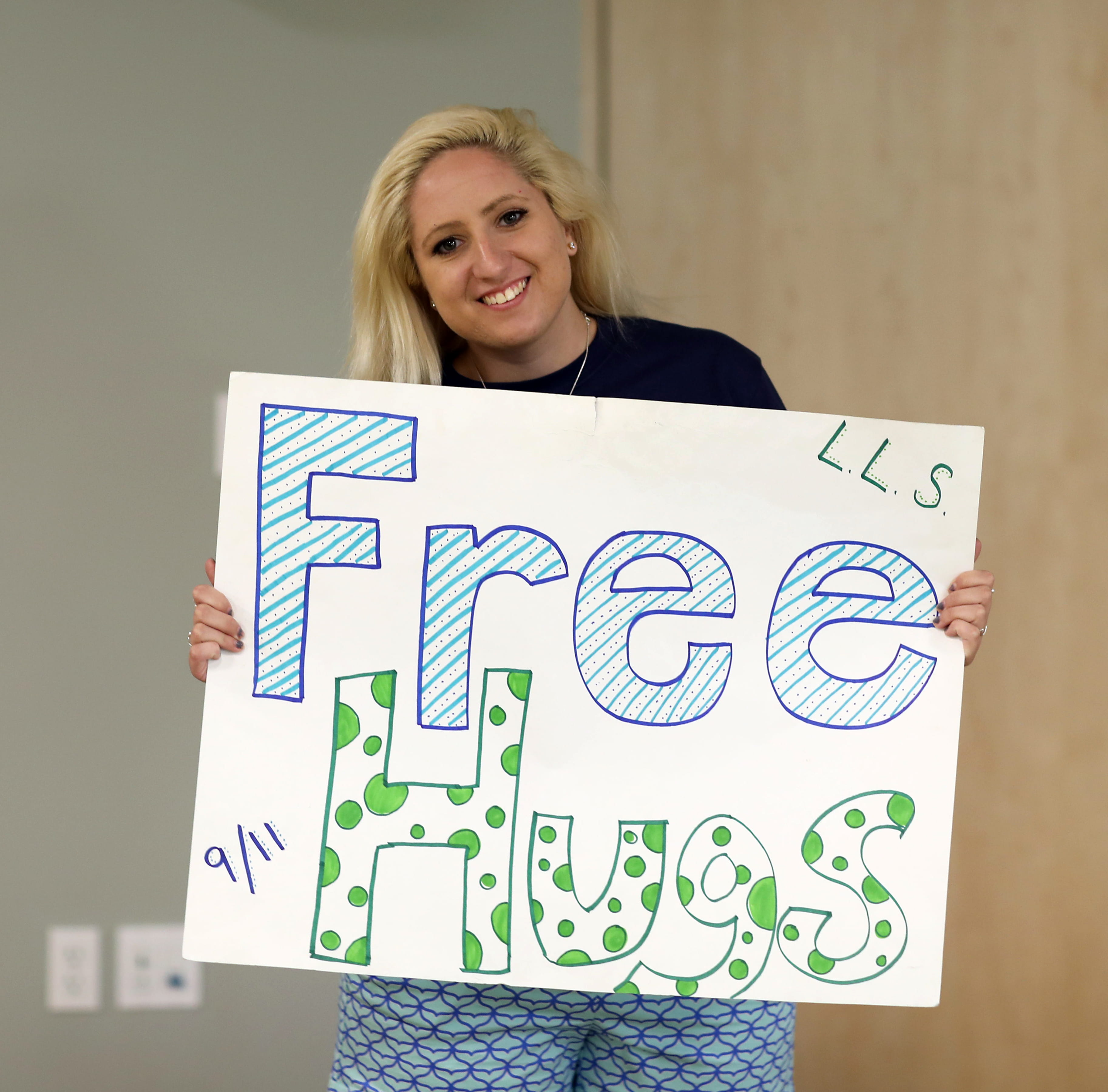 a woman holding a 'free hugs' sign