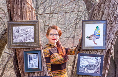 Artist Zoe Matthiessen poses with some of her work outside in the woods