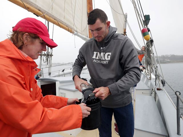 Mari Butler and student in oceanography course examine species from the ocean on a class field study trip. 