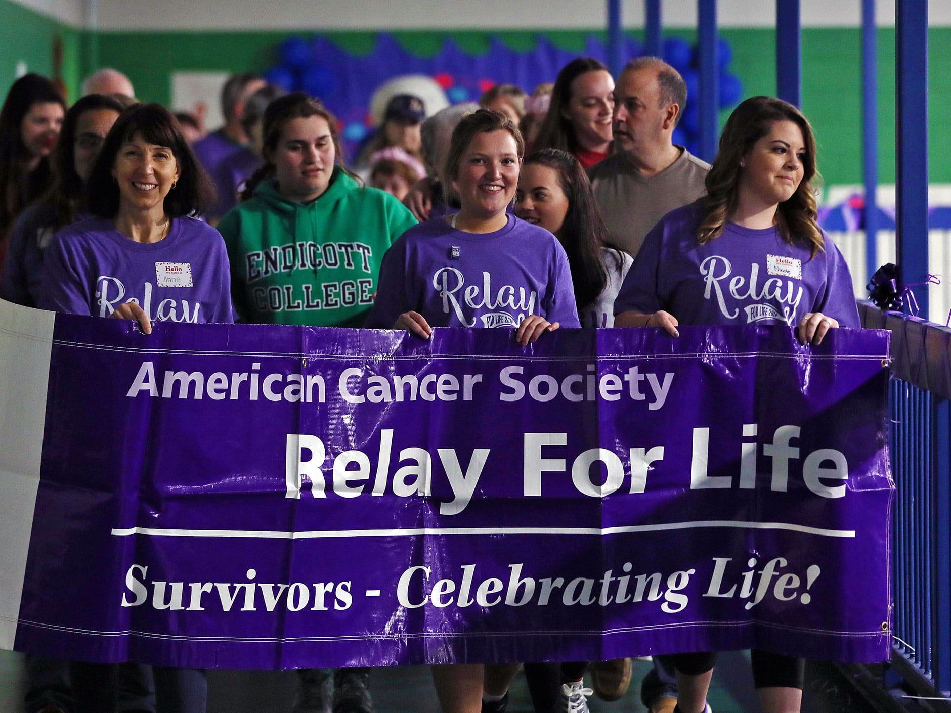 Relay for Life participants walking with a sign that reads "American Cancer Society, Relay for Life: Survivors—Celebrating Life!"