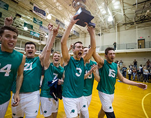 Men's volleyball student-athletes hoisting the NECC championship trophy
