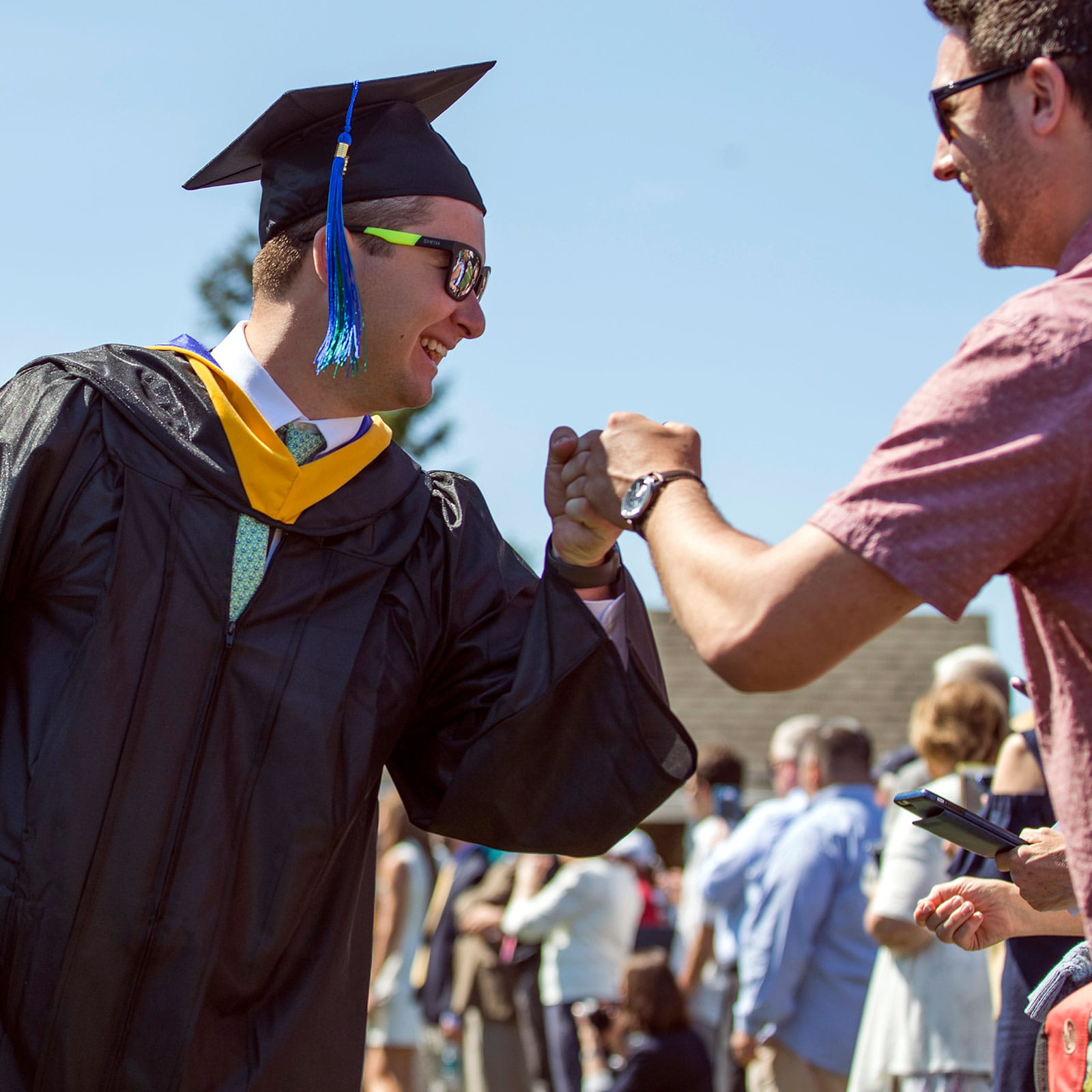 Graduate giving a fist bump to family member