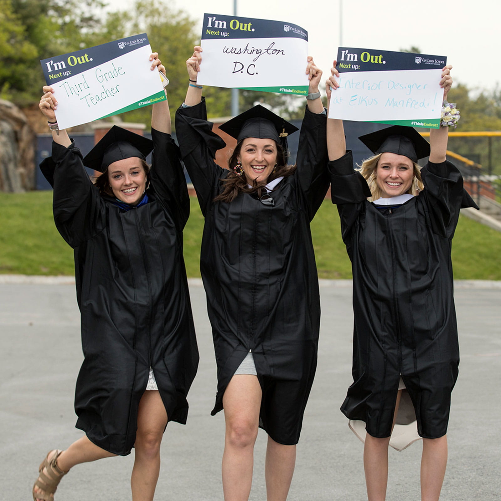 Three graduates holding up social media signs