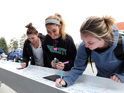 Students signing a beam that was placed in Phase I of the Wax Academic Center