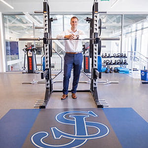 Jameson Pelkey leaning over a squat rack inside the St. John's Prep Wellness Center