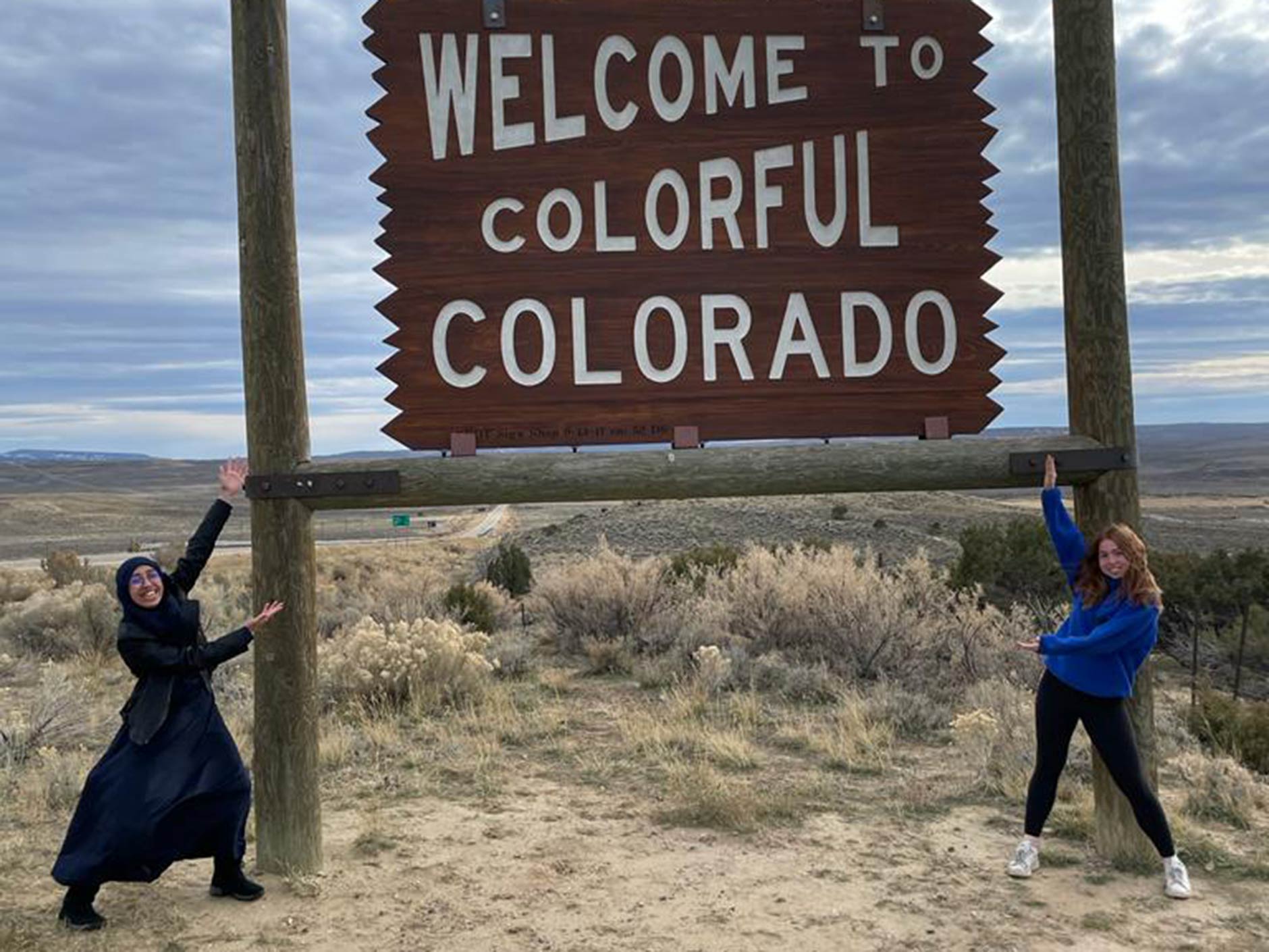 two girls posing in front of colorado sign