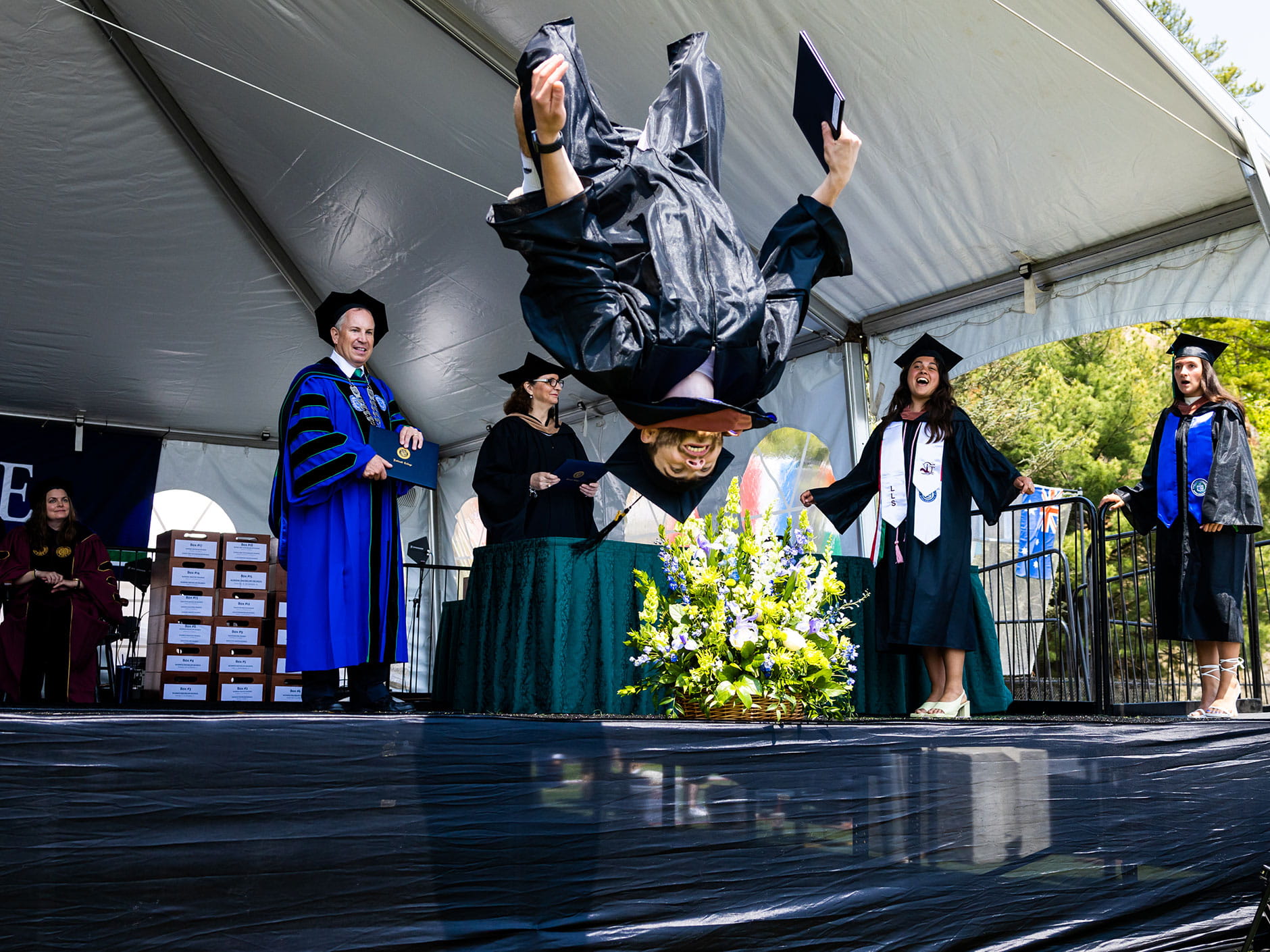 A student jumps off stage after receiving his degree