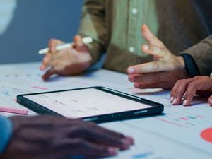 A close-up view of several people collaborating around a table with the focus is on their hands