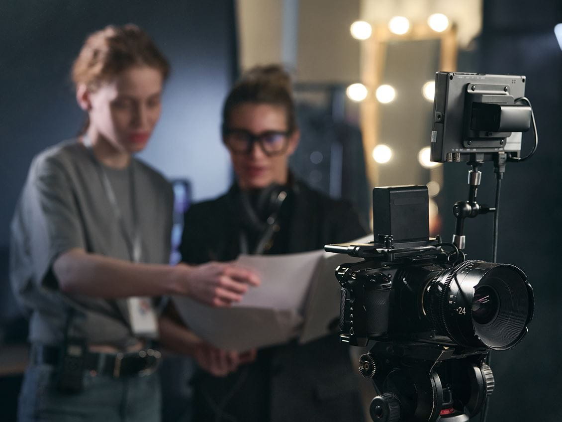 Two women working behind a film camera