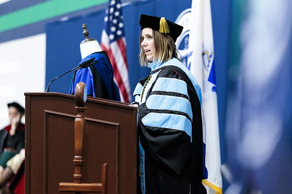 Professor Alyssa Czarnecki, School of Sport Science, at a podium during Inauguration & Convocation at Endicott College