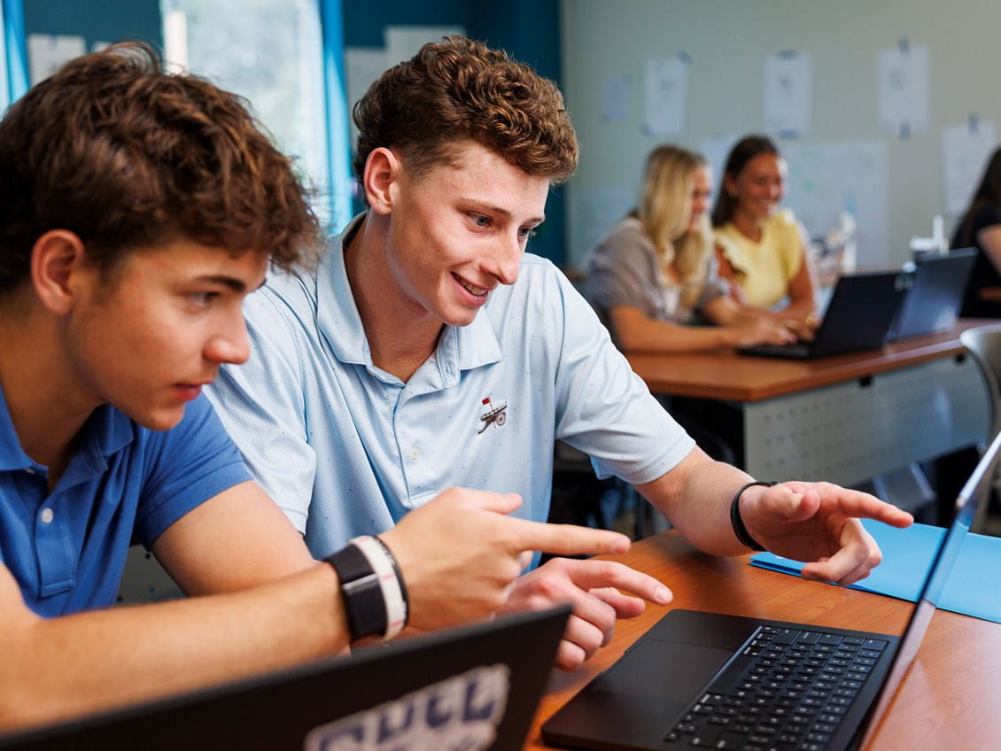 Students gathered around a computer looking happy
