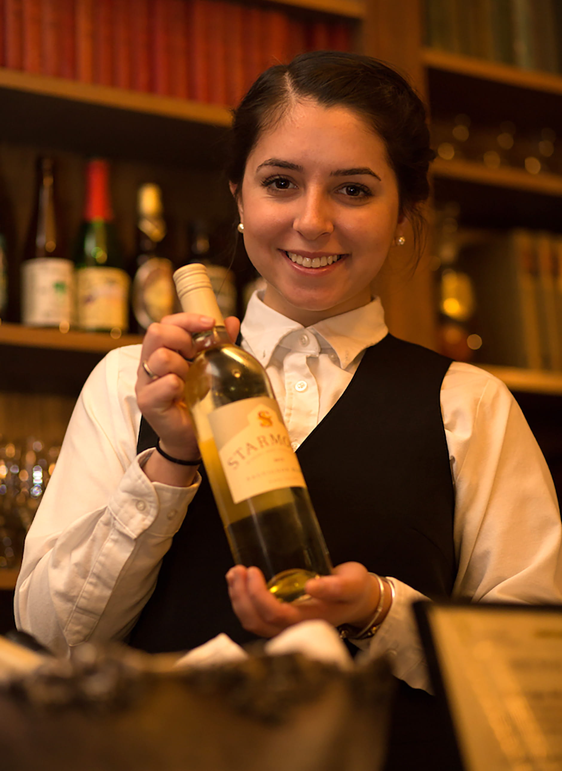 An Endicott College Hospitality Management student prepares a bottle of wine for a tasting event.