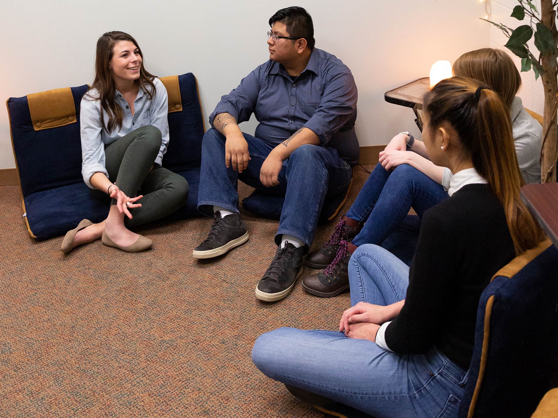 Four students sitting on the floor having a discussion