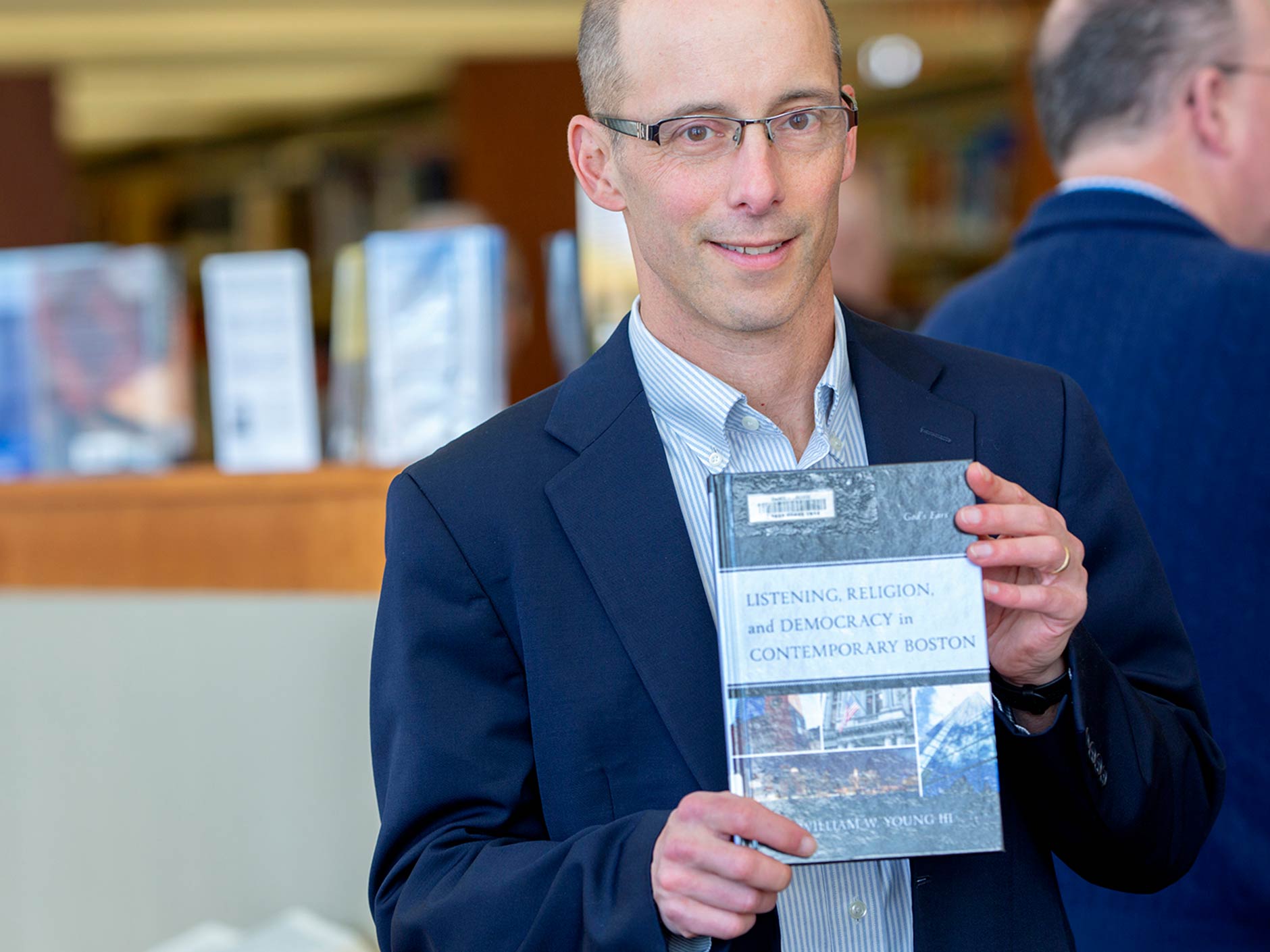 William Young Faculty Author in the library holding up his  book