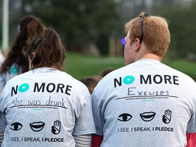 The back of two Endicott students wearing t-shirts in support of student health programs