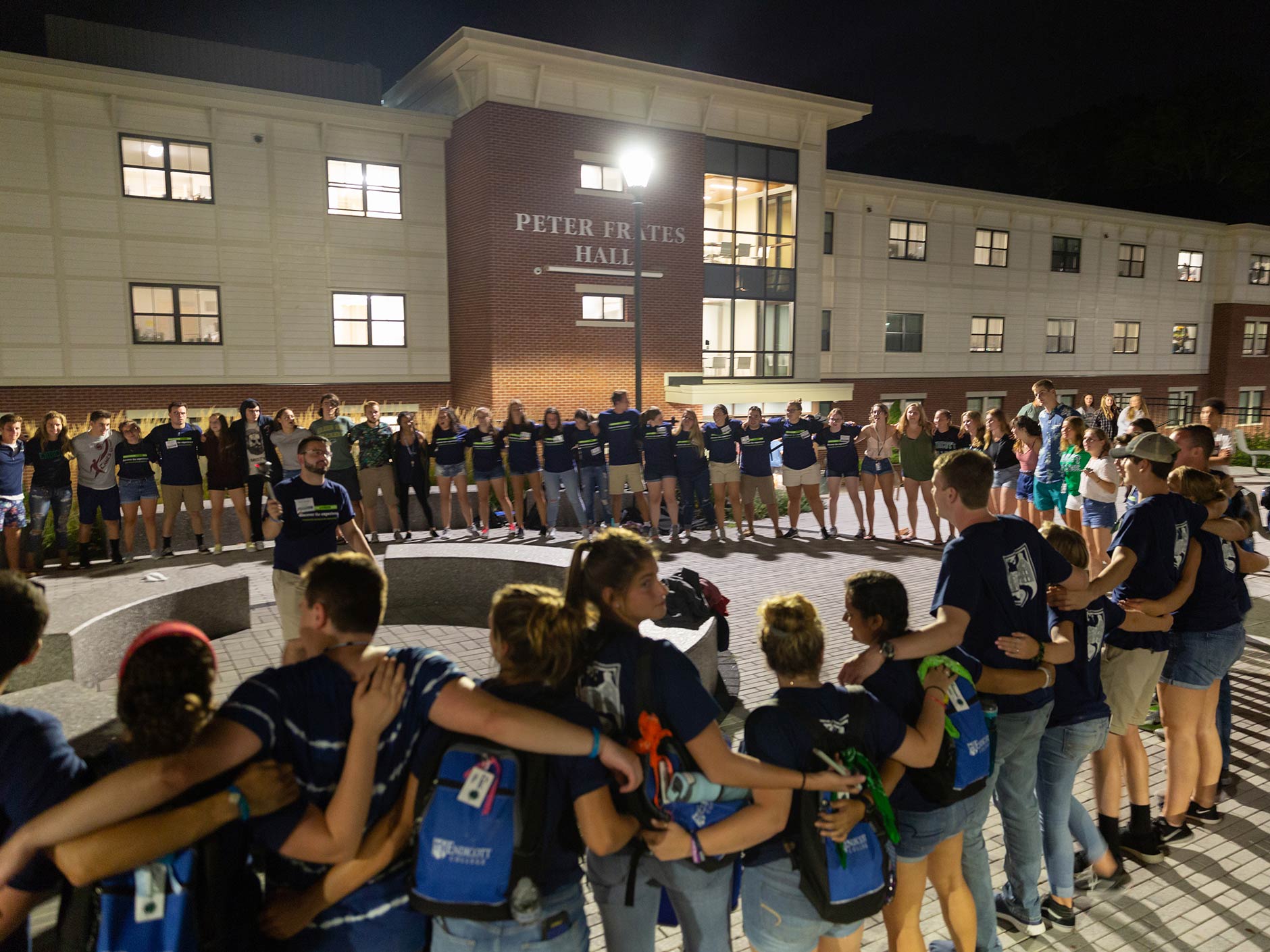 Students in a circle during orientation in front of Frates Hall during Fall orientation.