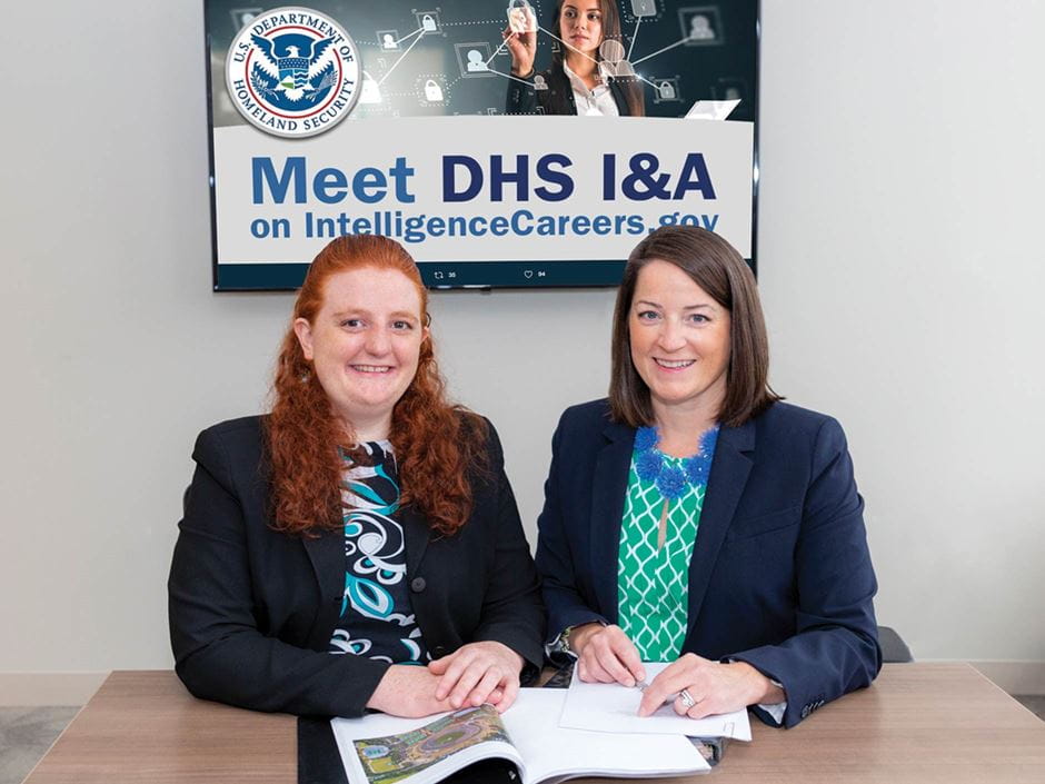 Endicott's Jaclyn Flaherty and Engrid Backstrom sitting in front of DHS sign