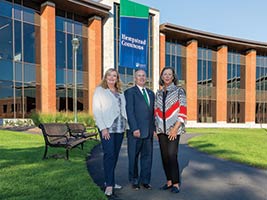 president of college and donors in front of new building
