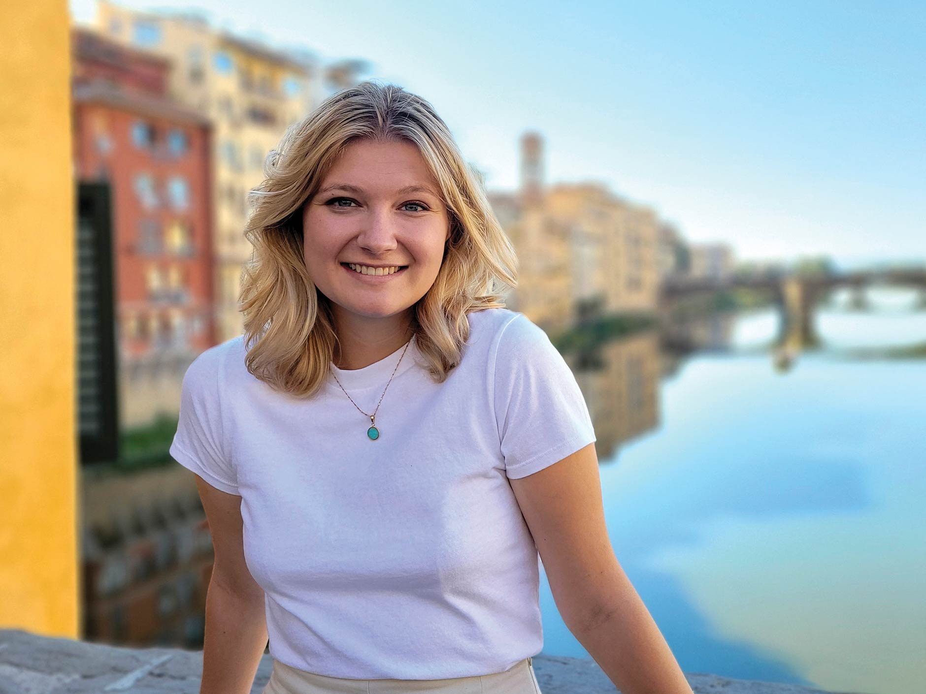 student poses in italy in front of water