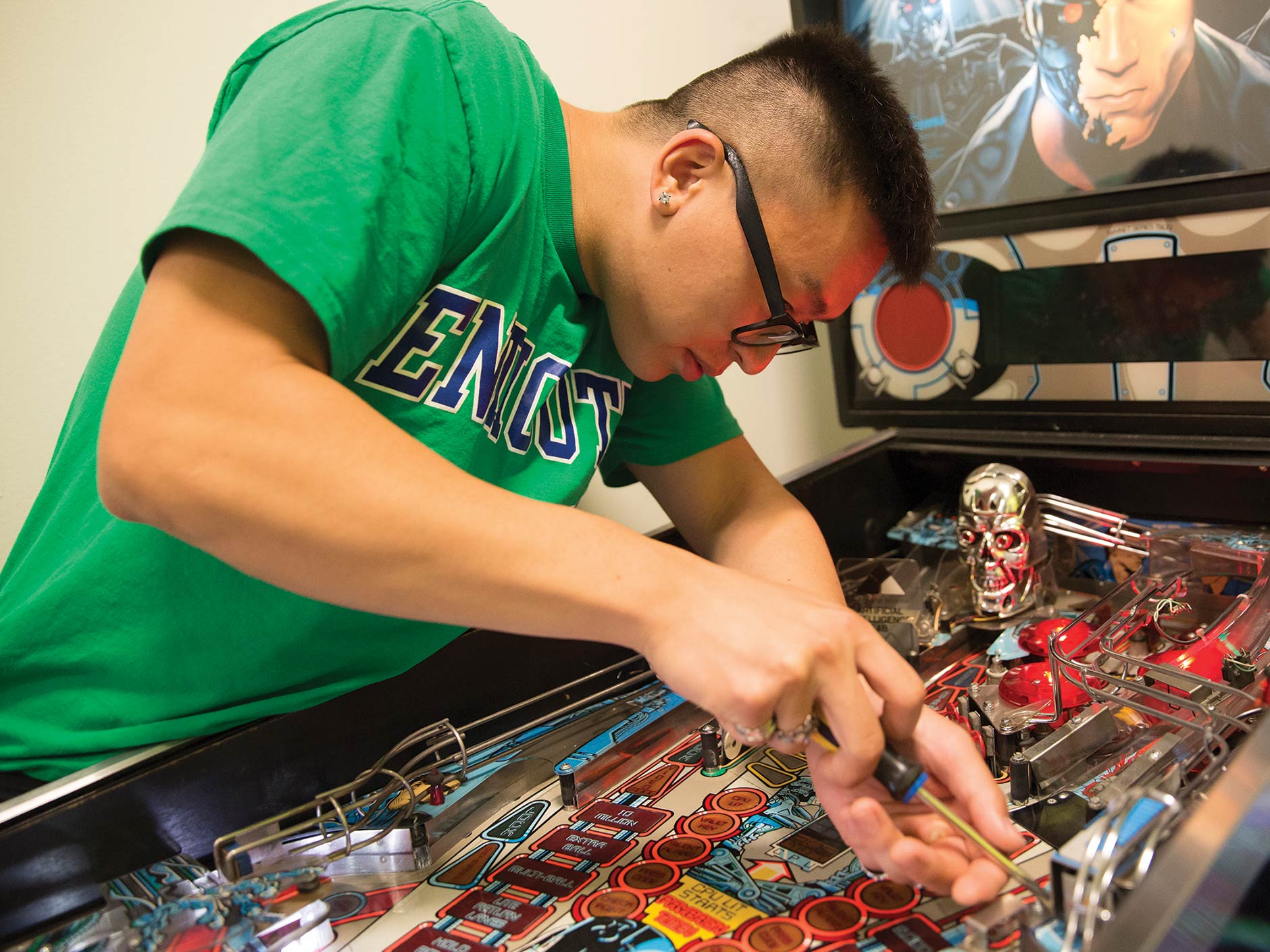 male student working on pinball machine
