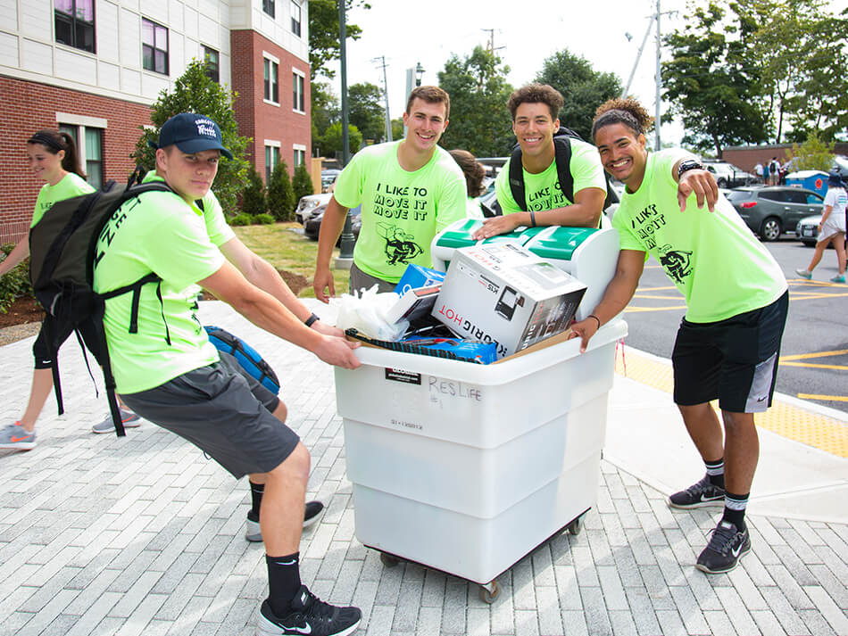 group of guys pulling/pushing cart full of belongings on move in day