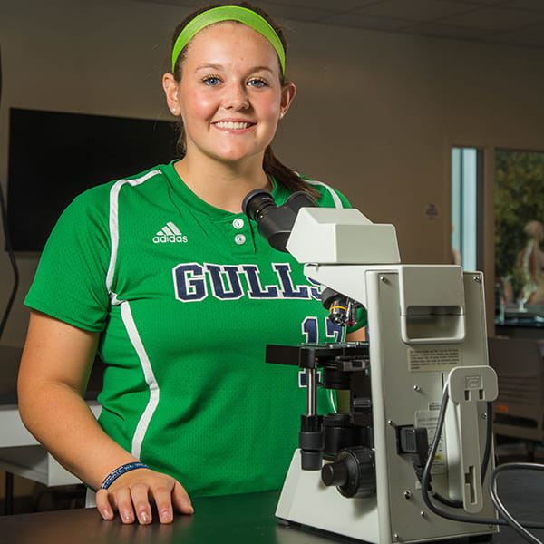 student athlete working with microscope in a lab