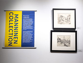 An art display featuring a yellow-and-blue banner on the left and two framed black-and-white etchings on the right.