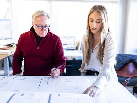 A male instructor and female student reviewing detailed architectural floor plans together.