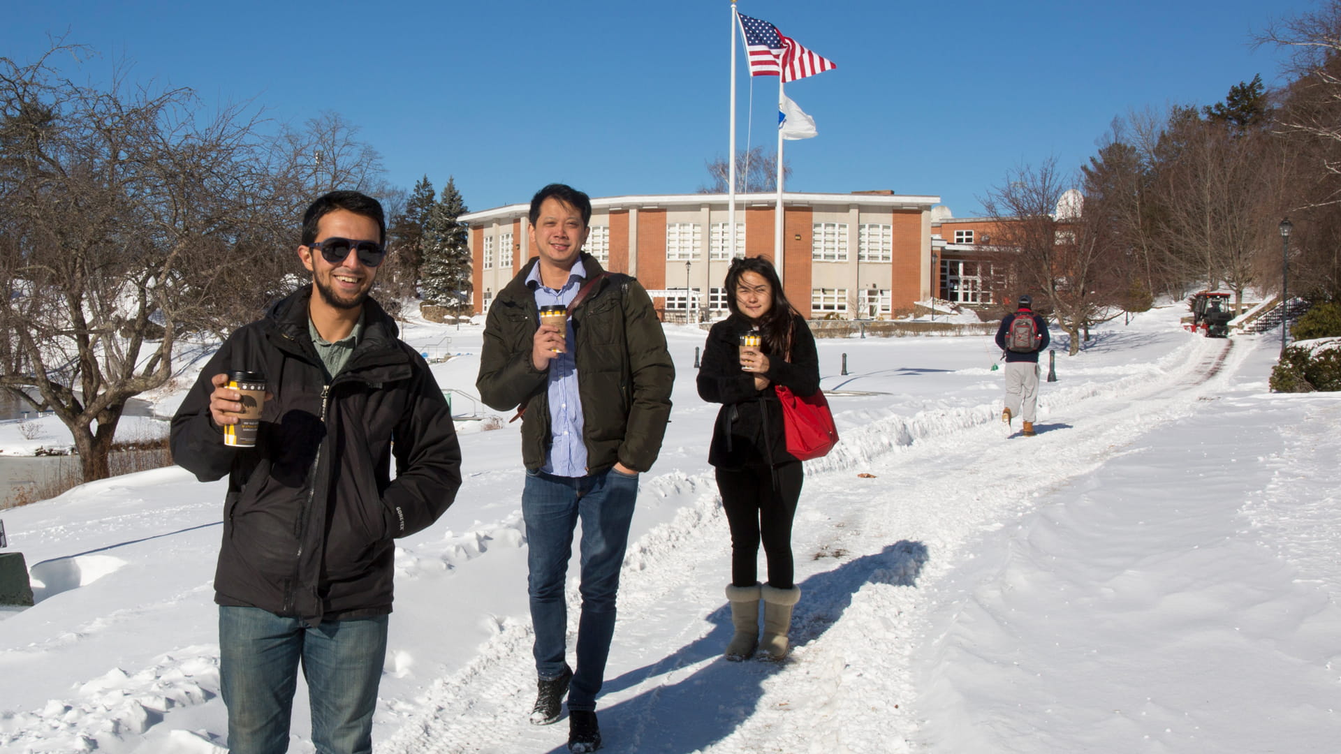 Three Endicott students walking from the academic center in the snow