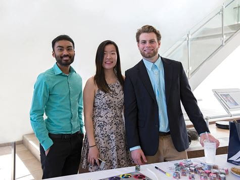 three students dressed up manning a table at event